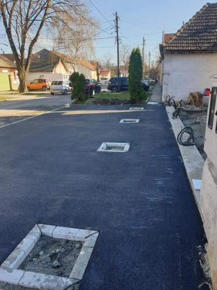 Frissen aszfaltozott járdaszakasz fa szigetekkel.